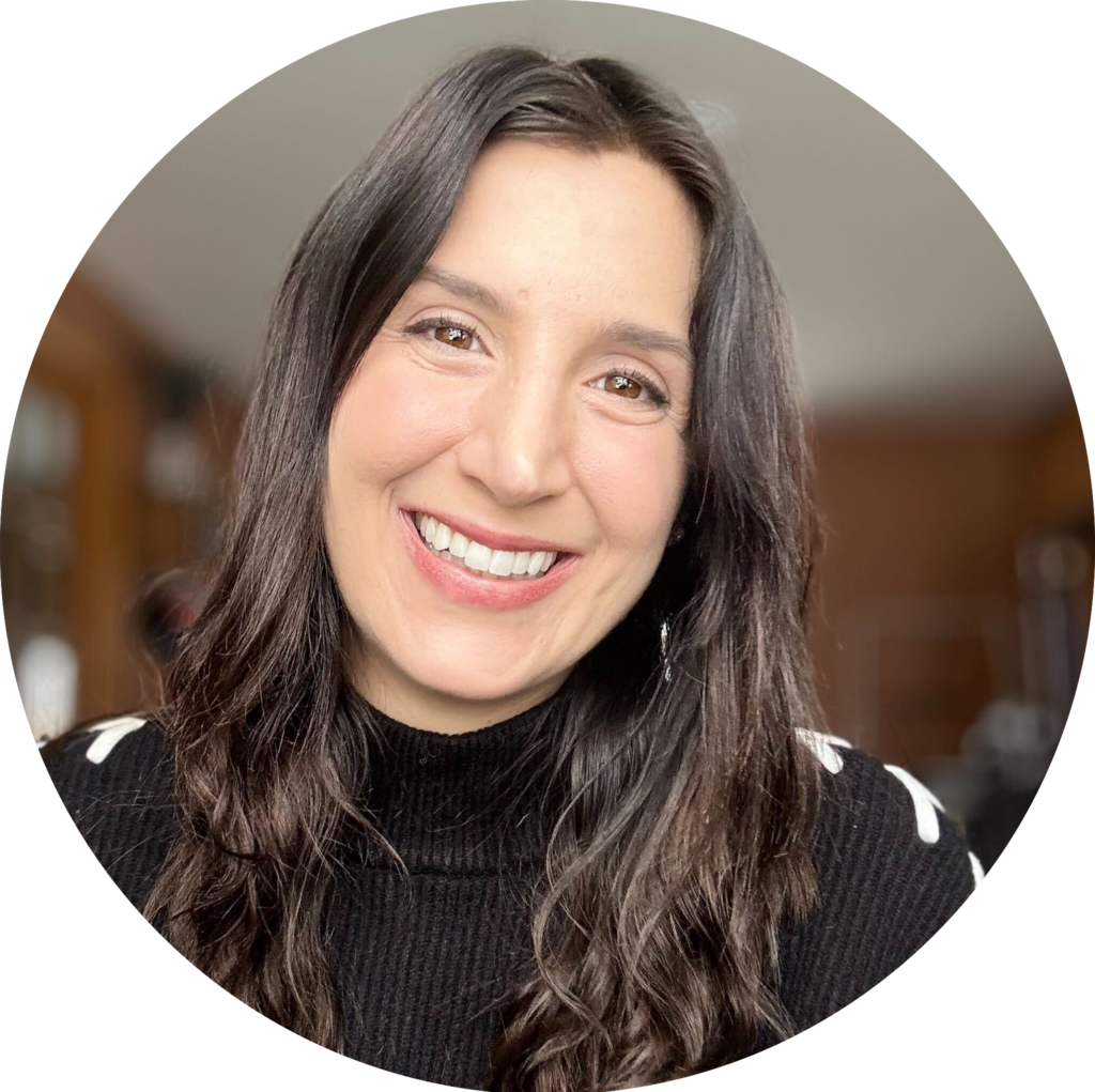 Smiling woman with long dark hair wearing a black sweater, indoors.